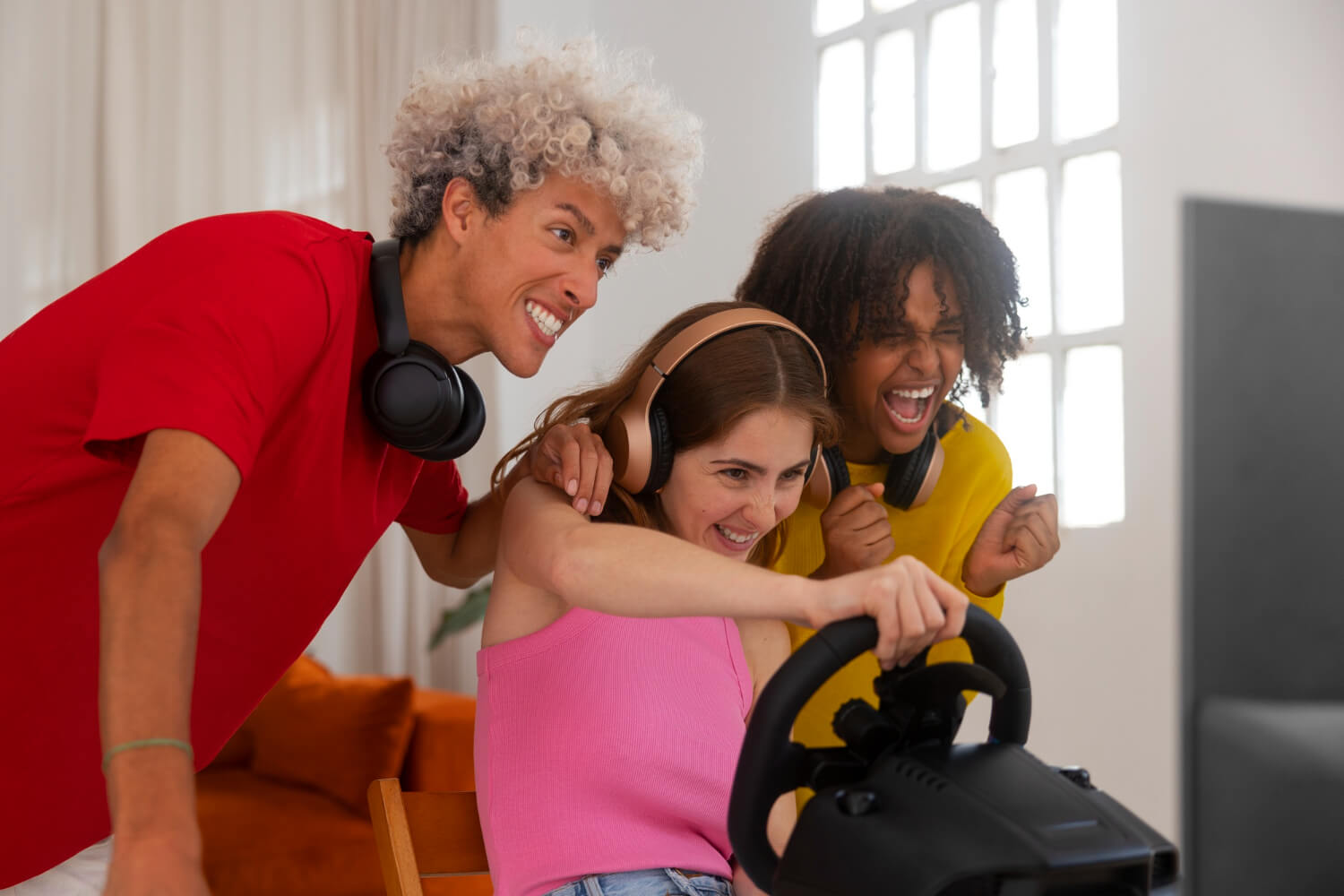 Três adolescentes felizes jogando videogame; a jovem ao centro sorri usando alinhadores invisíveis da Clínica Aliança em Itabaiana.